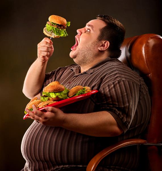 شکست رژیم غذایی مرد چاق در حال خوردن همبرگر فست فود فرد دارای اضافه وزن خوشحال با دهان باز با حرص در حال خوردن همبرگر بزرگ روی چنگال نفرت از رژیم های غذایی مفهوم صندلی های تجاری برای افراد چاق