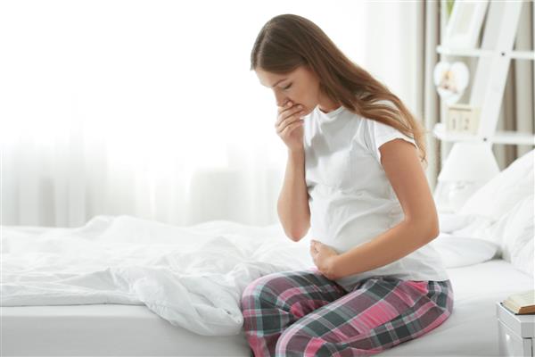 زن باردار جوانی که از تهوع صبحگاهی رنج می برد