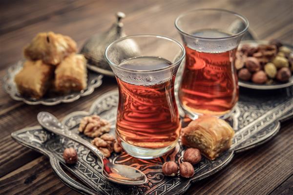 فنجان چای ترکی به سبک سنتی با تاخیر ترکی روی زمینه چوبی سرو می شود