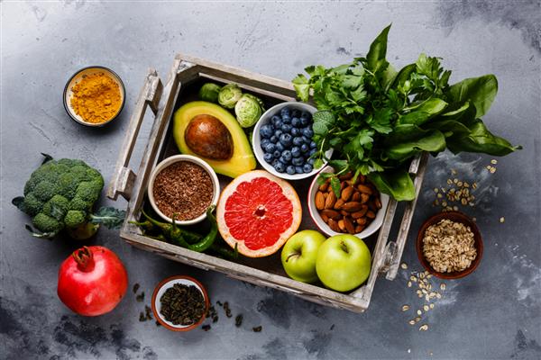 انتخاب غذای سالم در جعبه چوبی میوه سبزیجات دانه ها سوپر فود غلات سبزیجات برگ بر روی زمینه بتونی خاکستری