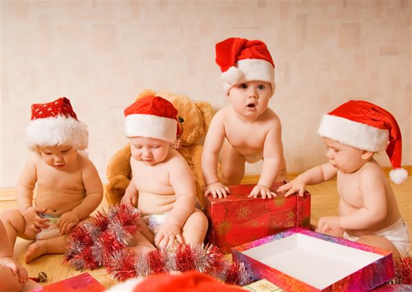 گروهی از کودکان نوپا شایان ستایش با کلاه های کریسمس در حال بسته بندی هدایا