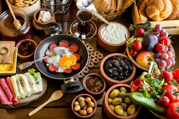 صبحانه سنتی دهکده ترکی با تابه تخم مرغ میوه های تازه ماست عسل و سبزیجات روی میز چوبی نمای بالا