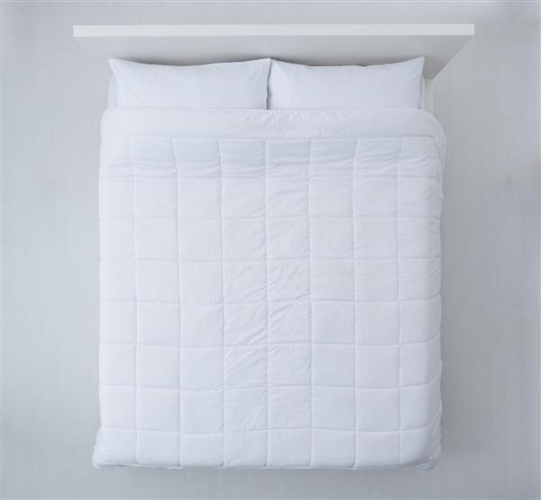 تختخواب شیک با لحاف سفید نرم ملافه و بالش نمای بالا