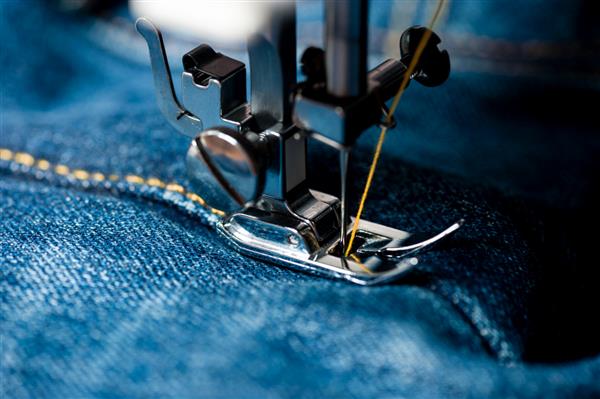 دوخت شلوار جین نیلی با چرخ خیاطی مفهوم صنعتی پوشاک
