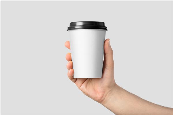 ماکت دست مردی که یک فنجان کاغذی قهوه جدا شده روی پس‌زمینه خاکستری روشن در دست دارد