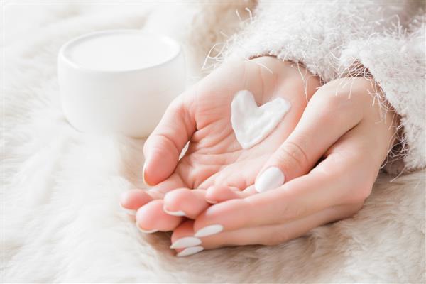 دست های زن آراسته زیبا با شیشه کرم روی پتوی کرکی کرم مرطوب کننده برای پوست تمیز و نرم در فصل زمستان شکل قلب ایجاد شده از کرم عاشق بدن مفهوم مراقبت های بهداشتی