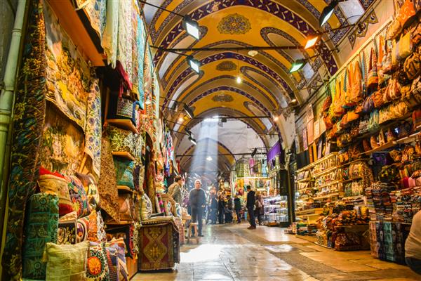 استانبول ترکیه - 2 دسامبر 2017 افرادی که در بازار بزرگ خرید می کنند بالش های دست ساز کیف و فرش روی دیوار برای فروش قرار دارند نور خورشید از پنجره سقف به داخل می آید