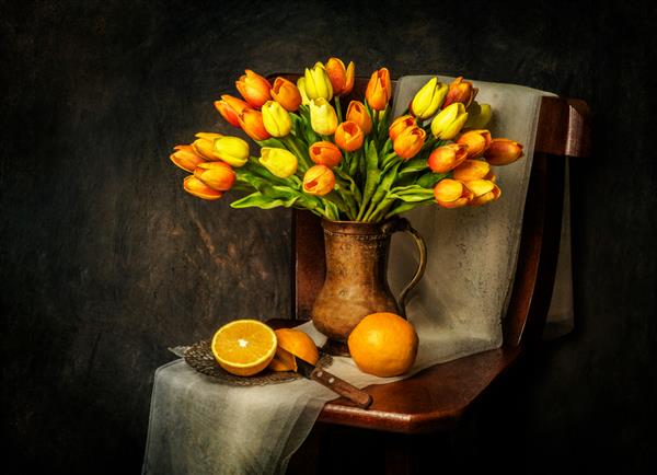 طبیعت بی جان کلاسیک با دسته گل لاله روی صندلی چوبی روستایی با پرتقال تازه و روسری قرار داده شده است