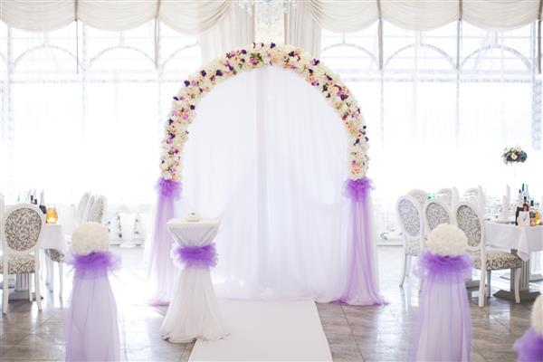طاق گل از رنگ های تازه برای مراسم عروسی در رستوران در زمینه سفید با دکور عروسی روشن