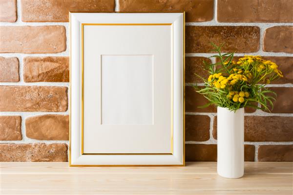 ماکت قاب تزئین شده با طلا با گل‌های زرد پررنگ وحشی در گلدان نزدیک دیوارهای آجری آشکار ماکت قاب خالی برای طراحی ارائه قالب بندی قالب برای هنر مدرن