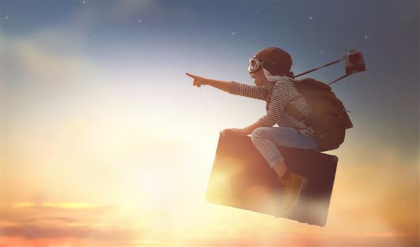 رویاهای سفر پرواز کودک روی چمدان در پس زمینه غروب خورشید