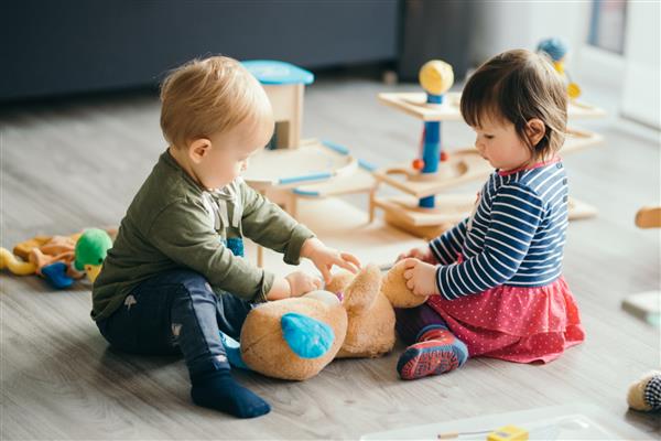 دختر و پسر بچه ناز در حال بازی با اسباب بازی ها در کنار خانه