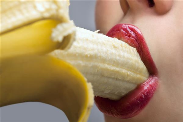 نمای نزدیک دهان زن در حال خوردن موز پوست کنده