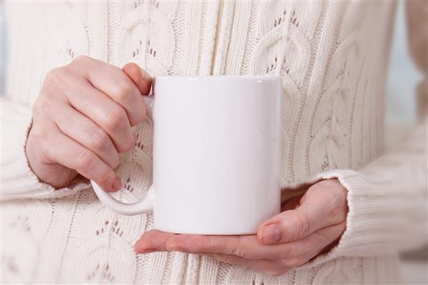دختری با پلیور گرم لیوان سفید در دست دارد ماکت طرح هدایای زمستانی