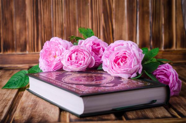 قرآن با گل رز روی میز چوبی مفهوم ماه رمضان تمرکز انتخابی