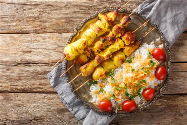 جوجه کباب یک کباب مرغ لذیذ ایرانی است که طعم بی نظیری زعفرانی دارد و با برنج در بشقاب روی میز سرو می شود نمای افقی از بالا