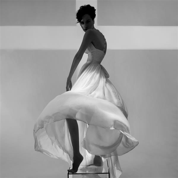 خانم جوان زیبا با لباسی شیک در یک استودیو عکس ژست گرفته است مدل سکسی در نورافکن های رنگی روشن پرتره زنی با لباس عروس سفید عکاسی هنری