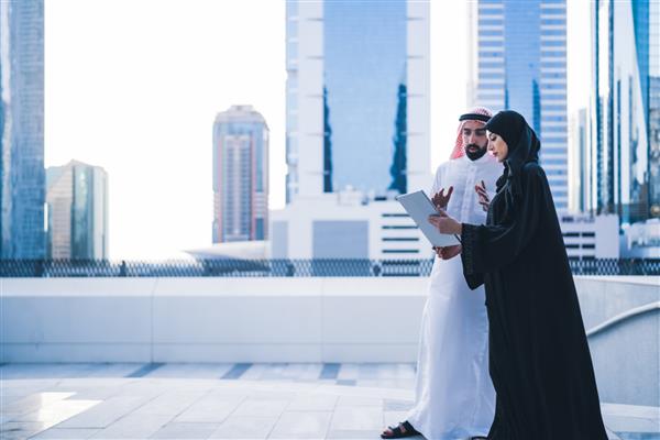 زوج‌های عرب یا همکارانی که با هم روی تبلت یا لپ‌تاپ با لباس‌های سنتی و عبایی کار می‌کنند کارمندان مسلمان زن و مرد بازرگان سعودی یا اماراتی