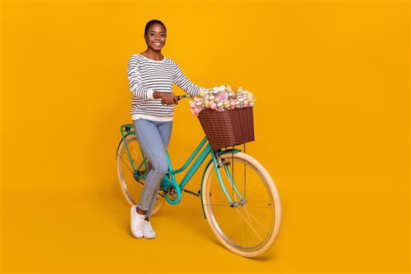 عکس کنار نمایه تمام طول بانوی جوان زیبا از رویداد سرگرمی دوچرخه سواری در اوقات فراغت با پس زمینه زرد جدا شده است