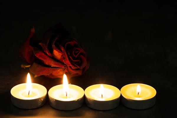 یک گل رز قرمز با شمع در زمینه تیره فضای عرفانی دراماتیک آیین جادوی سیاه مفهوم غم و اندوه
