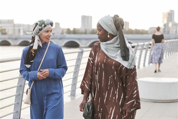 دو زن جوان با لباس های مسلمان در حال صحبت با یکدیگر در پیاده روی خود در شهر