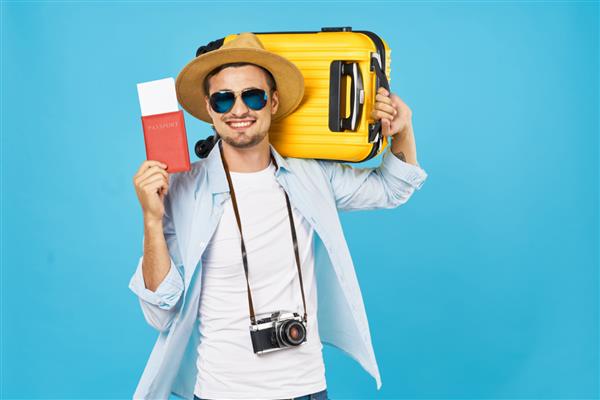 گردشگر مرد خوشحال با چمدان زرد رنگ که پاسپورت و بلیط ویزا در دست دارد