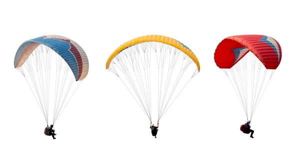 مجموعه چتر نجات رنگارنگ روشن جدا شده در پس زمینه سفید ورزشکار در حال پرواز بر روی پاراگلایدر مفهوم ورزش شدید چالش ماجراجویی