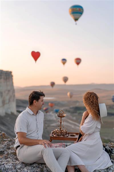یک زوج عاشق در میان بادکنک ها زوجی عاشق در کاپادوکیه زوج در ترکیه ماه عسل در کوهستان زن و مرد در سفر هستند پرواز با بالون هوای گرم عروسی سفر عشق