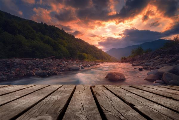 رودخانه کوهستانی سریع در زمان غروب زیبا با پل چوبی خالی منظره الگوی طبیعی