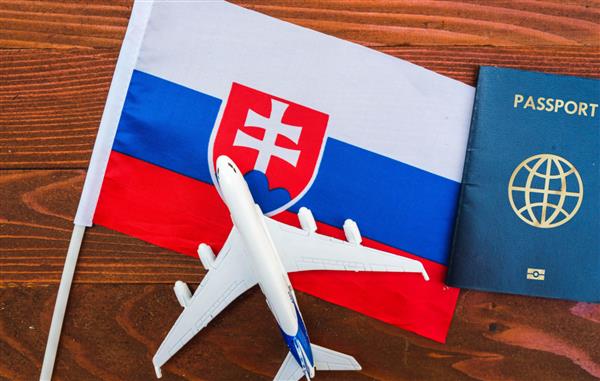 پرچم اسلواکی با گذرنامه و هواپیمای اسباب بازی در زمینه چوبی مفهوم سفر با پرواز