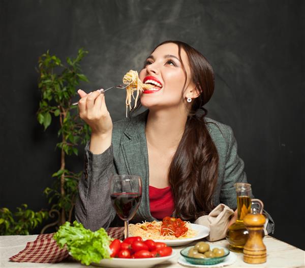 زن جوان شاد در حال خوردن پاستا در رستوران