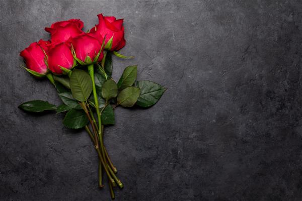 کارت تبریک روز ولنتاین با دسته گل رز قرمز روی پس زمینه سنگی تیره نمای بالا تخت خوابیده با فضایی برای احوالپرسی شما