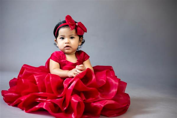 دختر کوچک آسیایی دوست داشتنی با لباس قرمز با شادی و خوشحالی در خانه خود بازی می کند و مهارت ها و خلاقیت خود را ارتقا می دهد
