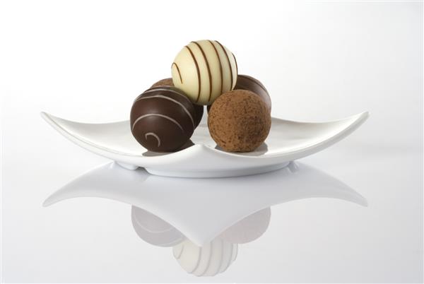 ترافل های شکلاتی در یک بشقاب سفید جدا شده روی پس زمینه سفید