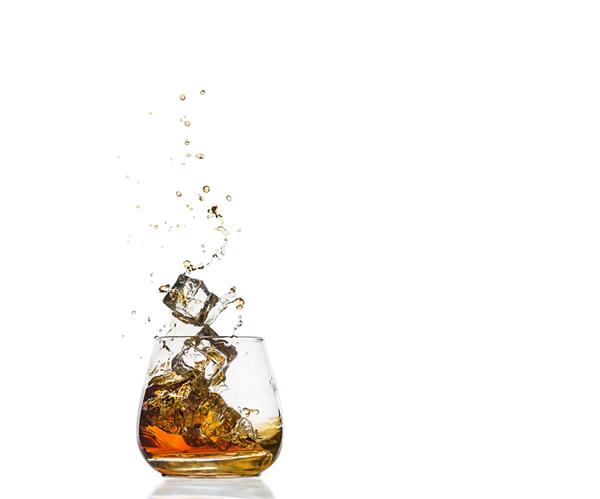 یک لیوان کنیاک با پاشیده شدن تکه یخ جدا شده روی سفید پاشش الکل ویسکی یا کنیاک یا نوع دیگری از الکل