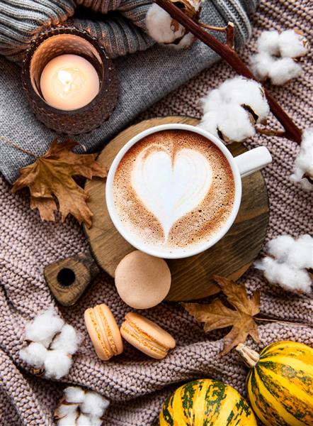 ترکیب زیبا و عاشقانه پاییزی با فنجان قهوه پتوی گرم کدو حلوایی راه راه تزئینی شمع و برگ های پاییزی صبح دنج داخلی خانه Hygge