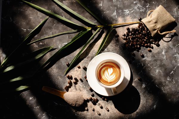 نمای نزدیک از فنجان قهوه سفید کاپوچینوی داغ با هنر لاته به شکل قلب و گل مفهوم غذا و نوشیدنی