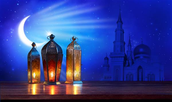 فانوس های ماه رمضان روی میز با ماه و مسجد در زمینه آبی تیره کارت تبریک زیبا با فضای کپی برای تعطیلات مسلمانان چراغ عربی منور رسانه های ترکیبی