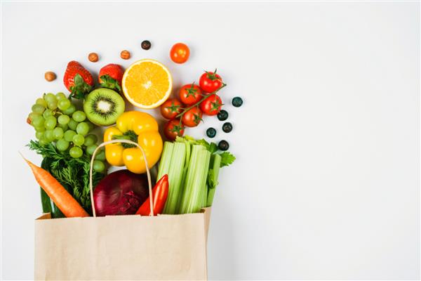 میوه ها و سبزیجات در پس زمینه روشن در یک کیسه کرافت از فروشگاه غذای سالم و سالم از بازار کشاورزان فضایی برای متن