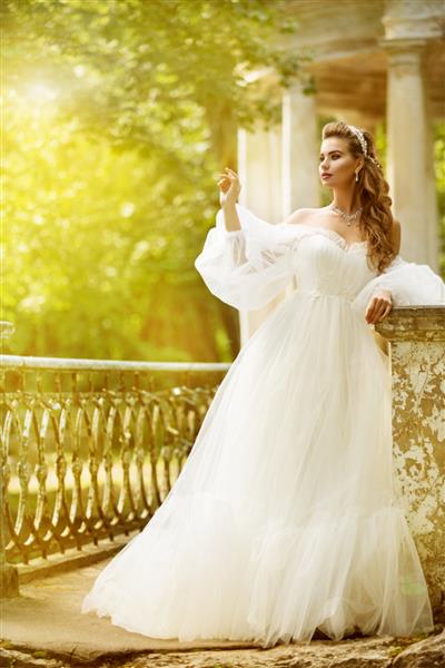 پرتره عروس در فضای باز مدل مد عروسی زیبا با لباس سفید زیبا پارک آفتابی تابستانی
