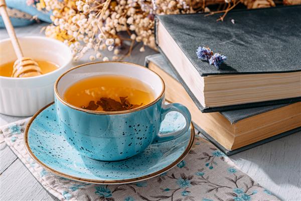 یک فنجان چای خوش طعم و معطر بهاری در یک لیوان آبی در آفتاب صبح