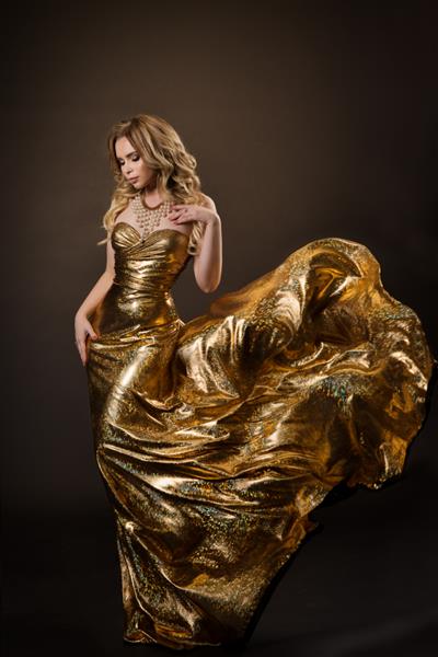 زن رقصنده با لباس طلایی که روی باد پرواز می کند بانوی زیبا با لباس طلایی درخشان و بالنده