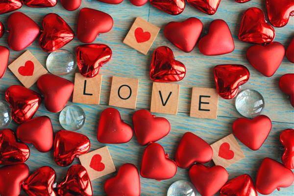 عشق در مربع های چوبی نوشته شده است قلب های قرمز و زمینه چوبی سبز