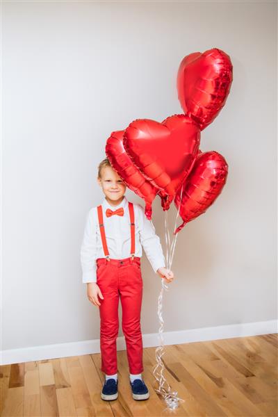 پسر سفید قفقازی که بادکنک قلبی قرمز در دست دارد مفهوم روز ولنتاین