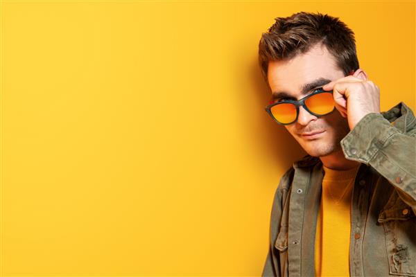 پرتره ای از یک مرد جوان شیک پوش که در استودیو روی پس زمینه زرد ژست گرفته است مد گاه به گاه برای مردان زیبایی سبک