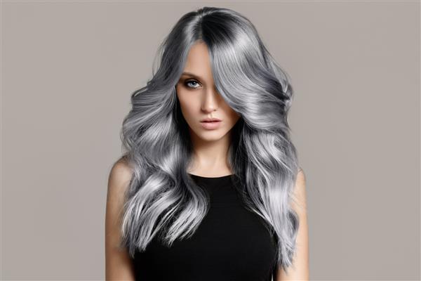 زن زیبا با موهای رنگ آمیزی موج دار بلند پس زمینه خاکستری تخت