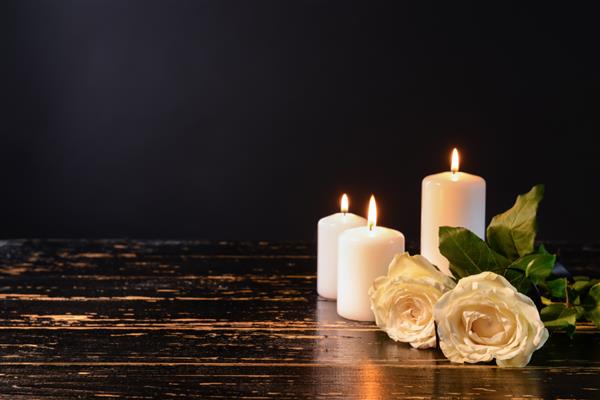سوزاندن شمع و گل روی میز در برابر پس زمینه سیاه