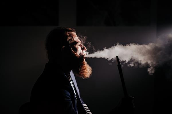 مرد ریشو در حال کشیدن قلیان در اتاقی تاریک سبک زندگی قلیان و مفهوم سیگار کشیدن پرتره یک ملوان با قلیان