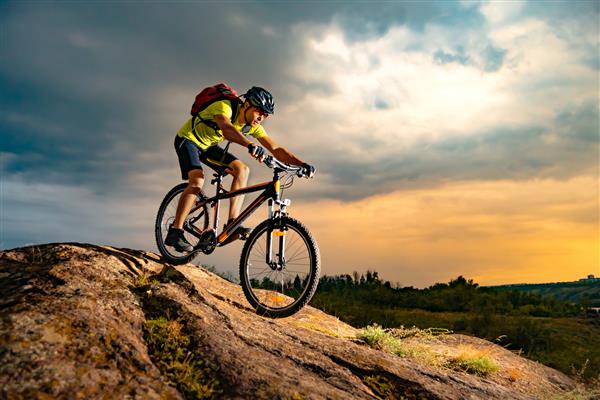 دوچرخه سوار دوچرخه سواری کوهستان در مسیر صخره ای در غروب آفتاب کانسپت دوچرخه سواری اسپرت و اندرو