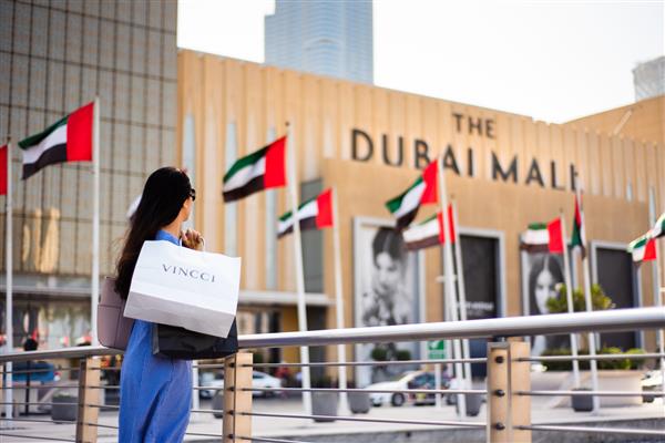 دبی امارات متحده عربی - 26 مارس 2018 گردشگر آسیایی در مقابل ورودی اصلی مرکز خرید دبی با کیسه های خرید